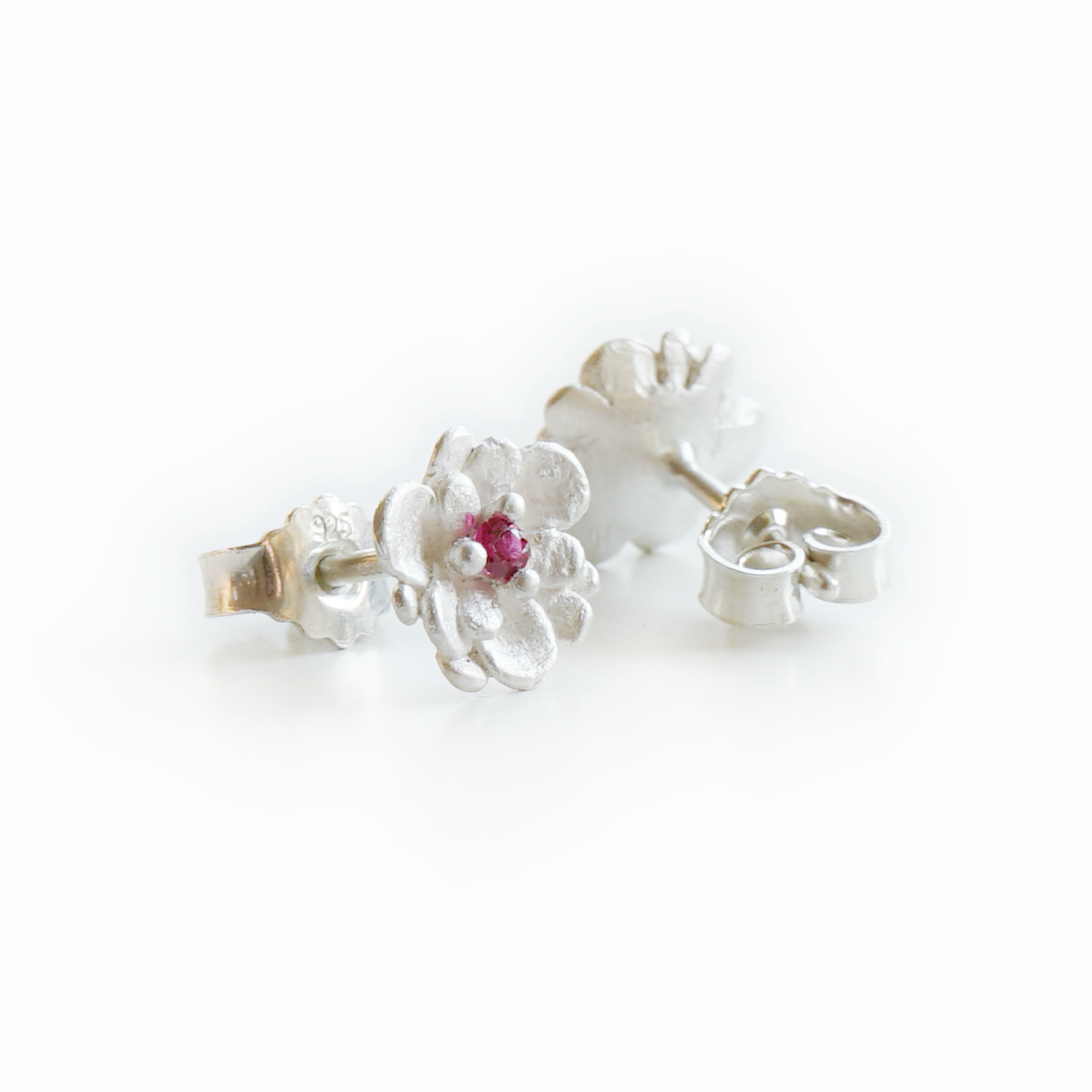 Pair of handcrafted floral stud earrings in recycled 925 sterling silver, showing front with pink sapphire and back with 925 stamp